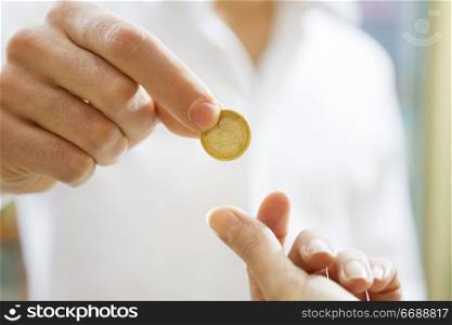 man paying 1 euro to the cashier in a store. Close up of the coin and some copy space