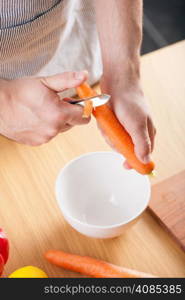 man peeling carrot in kitchen