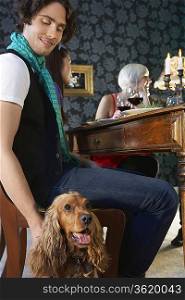 Man petting dog sitting near dining table
