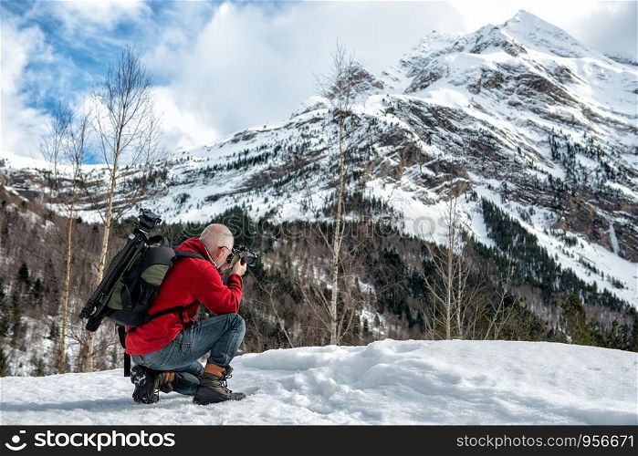 man photographer take a picture in the snowy mountains