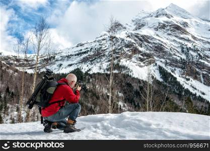 man photographer take a picture in the snowy mountains