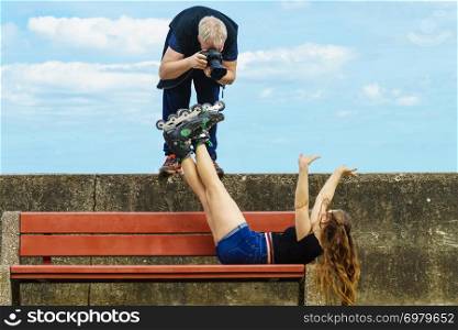 Man photographer taking crazy picture of fashion sporty women model wearing roller skates.. Man photographing roller skater woman