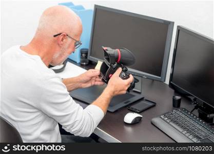 man photographer with camera at office with computer