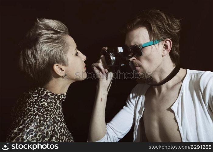 Man photographing a young woman in the studio on a black background