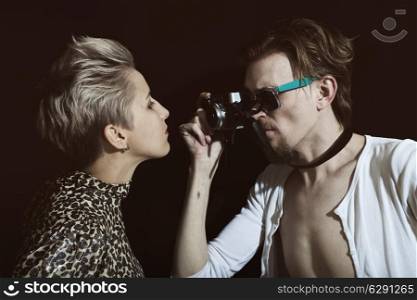 Man photographing a young woman in the studio on a black background
