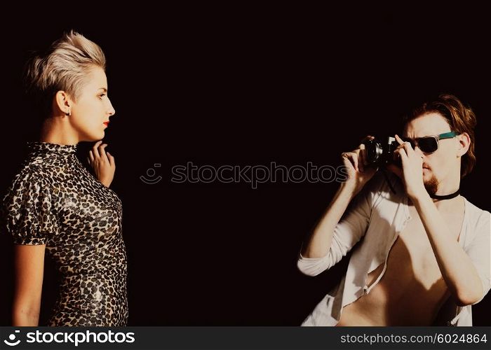 Man photographing a young women in the studio on a black background
