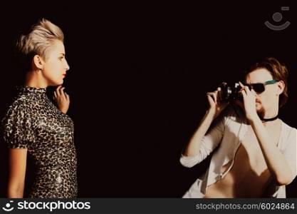 Man photographing a young women in the studio on a black background