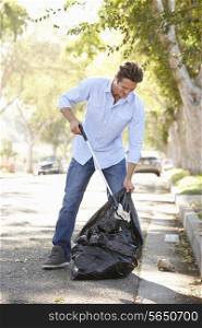 Man Picking Up Litter In Suburban Street