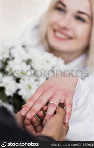 man placing diamond engagement ring finger his fiancee