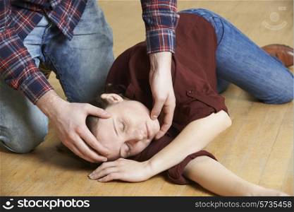 Man Placing Woman In Recovery Position After Accident