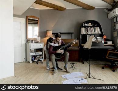 Man playing acoustic guitar for daughter in living room at home