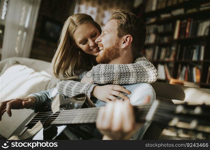 Man playing acoustic guitar for his young beautiful woman