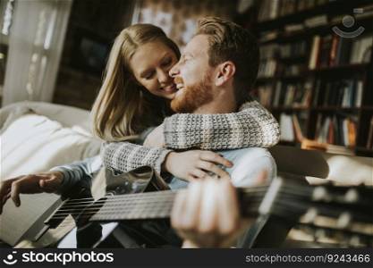 Man playing acoustic guitar for his young beautiful woman