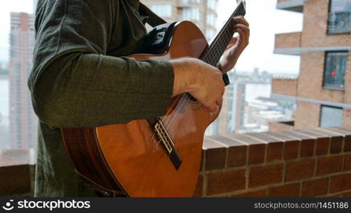 Man Playing Acoustic Guitar on Balcony