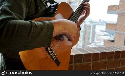 Man Playing Acoustic Guitar on Balcony