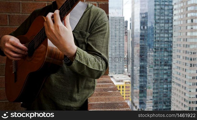 Man Playing Acoustic Guitar on Balcony