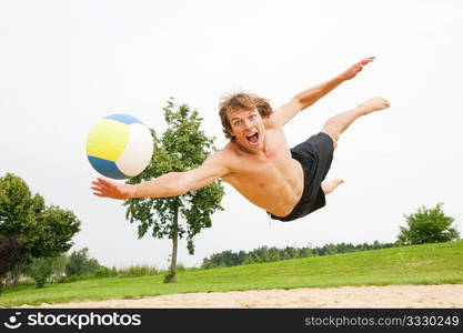 Man playing beach volleyball diving after the ball