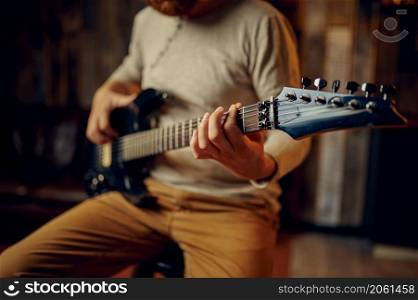 Man playing electric guitar. Cropped shot. Focus hand on fretboard with strings. Muscic lesson. Young man playing electric guitar cropped shot