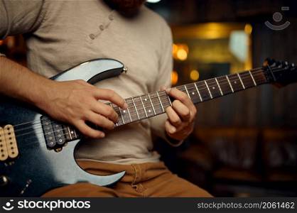 Man playing electric guitar. Cropped shot. Focus hand on fretboard with strings. Muscic lesson. Young man playing electric guitar cropped shot