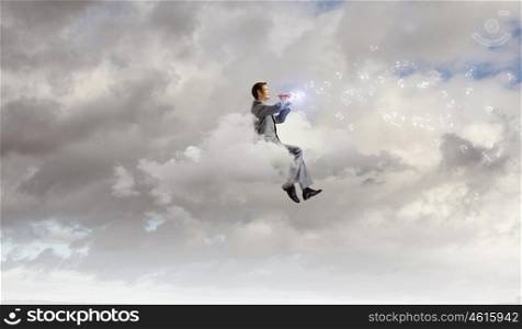 Man playing flute. Young carefree businessman sitting on cloud and playing flute