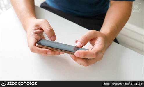 Man playing game on mobile phone. gamer boy playing video games holding Smartphoneworking mobile devices. cell telephone technology e-commerce concept.