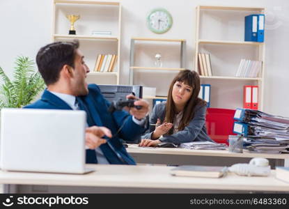 Man playing games in office while colleague is busy