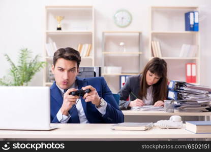 Man playing games in office while colleague is busy