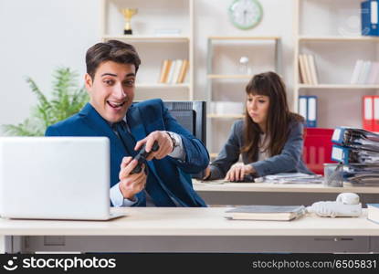 Man playing games in office while colleague is busy