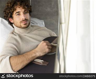 man playing guitar from car while road trip with copy space