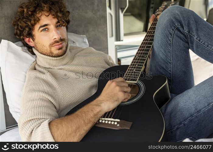 man playing guitar his car while road trip