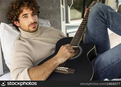 man playing guitar his car while road trip