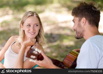 man playing guitar to girlfriend