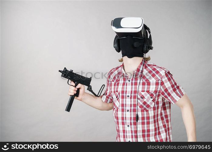 Man playing video game wearing virtual reality device holding gun. Gaming equipment for gamers concept.. Gamer man wearing VR holding gun