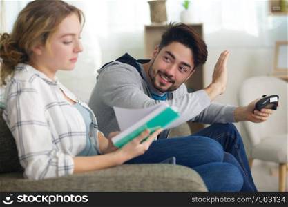 man playing video games and woman reading book