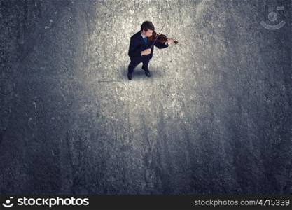 Man playing violin. Top view of young businessman playing violin
