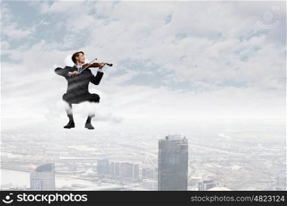 Man playing violin. Young businessman sitting on cloud and playing violin