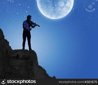 Man playing violin. Young man playing violin at night under moon light