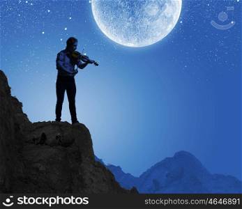 Man playing violin. Young man playing violin at night under moon light