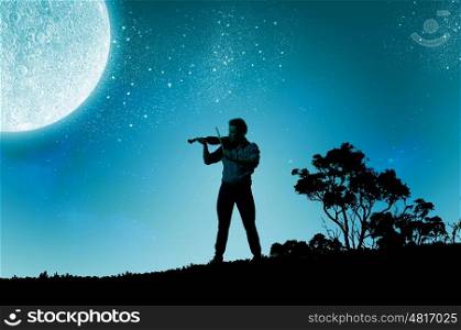 Man playing violin. Young man playing violin at night under moon light