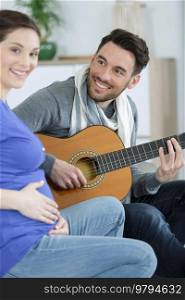 man plays gitar for pregnant woman