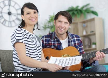 man plays guitar and woman holds sheet music