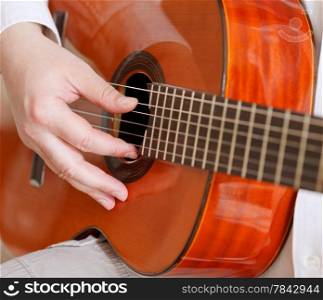 man plays on typical acoustic guitar close up
