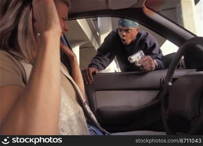 Man pointing a gun at a woman in a car