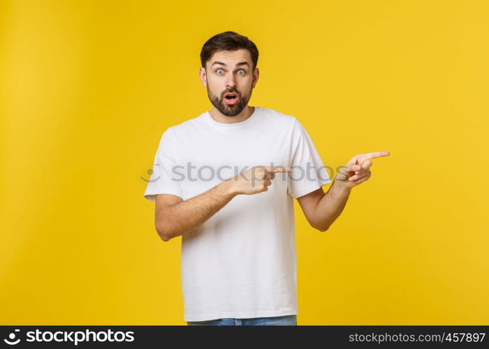 Man pointing showing copy space isolated on yellow background. Casual handsome Caucasian young man. Man pointing showing copy space isolated on yellow background. Casual handsome Caucasian young man.