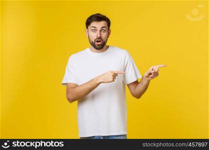 Man pointing showing copy space isolated on yellow background. Casual handsome Caucasian young man. Man pointing showing copy space isolated on yellow background. Casual handsome Caucasian young man.