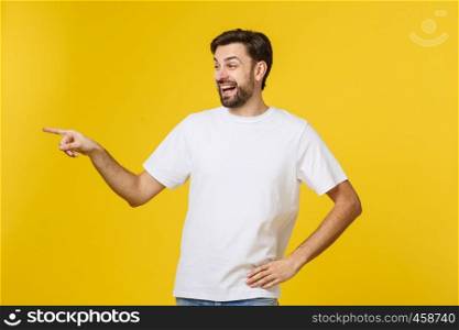 Man pointing showing copy space isolated on yellow background. Casual handsome Caucasian young man. Man pointing showing copy space isolated on yellow background. Casual handsome Caucasian young man.