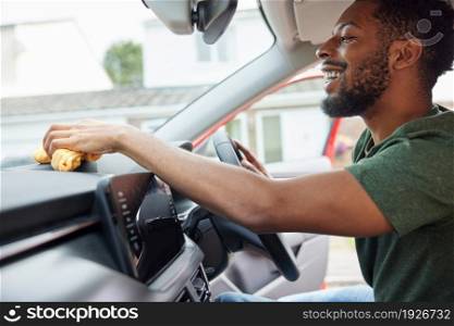 Man Polishing And Cleaning Dashboard Of Car During Car Valet