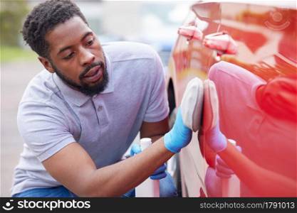 Man Polishing Bodywork Of Car During Valet
