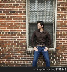 Man posing against a brick wall
