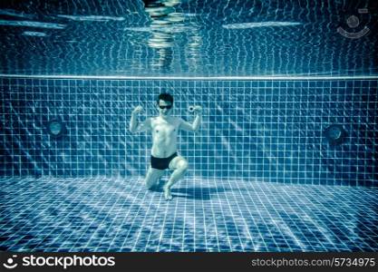 Man posing as Superman underwater swimming pool